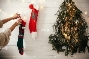 Stylish girl in cozy sweater hanging christmas stockings, decorating  festive room with garland light and christmas tree on white wall . Merry  Christma Stock Photo - Alamy